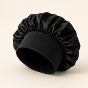 Black satin sleeping bonnet on warm ivory background