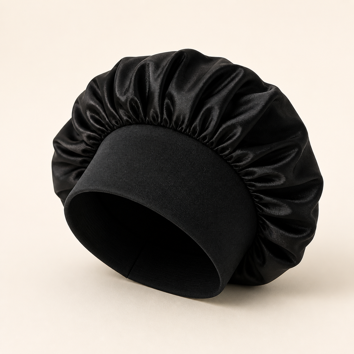 Black satin sleeping bonnet on warm ivory background